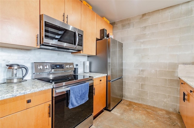 kitchen featuring light stone countertops, unfinished concrete floors, stainless steel appliances, and decorative backsplash