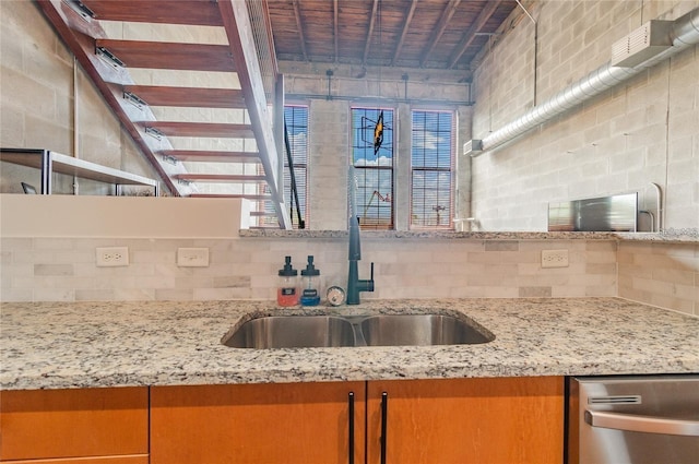 kitchen featuring backsplash, a sink, and light stone countertops