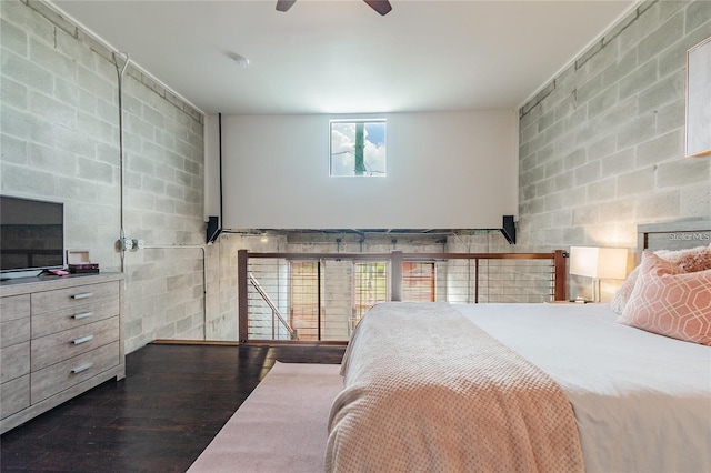 bedroom featuring ceiling fan, wood finished floors, and concrete block wall