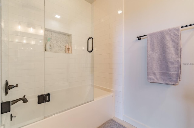 bathroom featuring combined bath / shower with glass door and baseboards