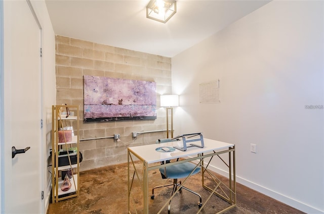 office area with concrete block wall, unfinished concrete flooring, and baseboards