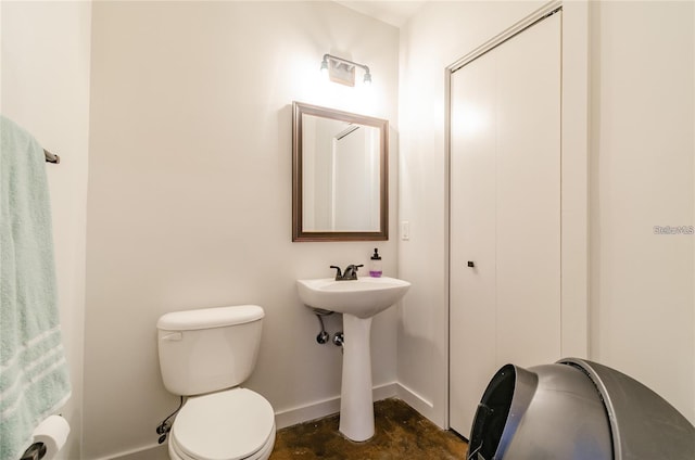 bathroom with concrete floors, a sink, toilet, and baseboards