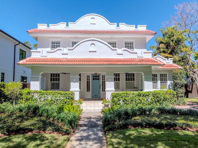 mediterranean / spanish-style house with covered porch, stucco siding, and a tile roof