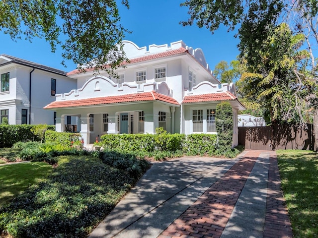 mediterranean / spanish-style house with stucco siding, fence, and a tiled roof