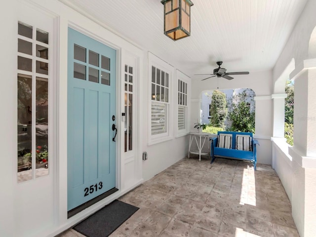 doorway to property with stucco siding, a porch, and a ceiling fan