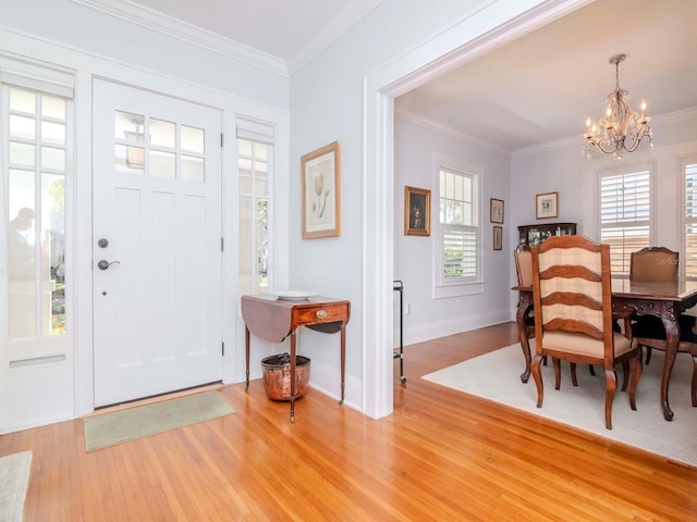 foyer with plenty of natural light, a notable chandelier, light wood-style flooring, and crown molding