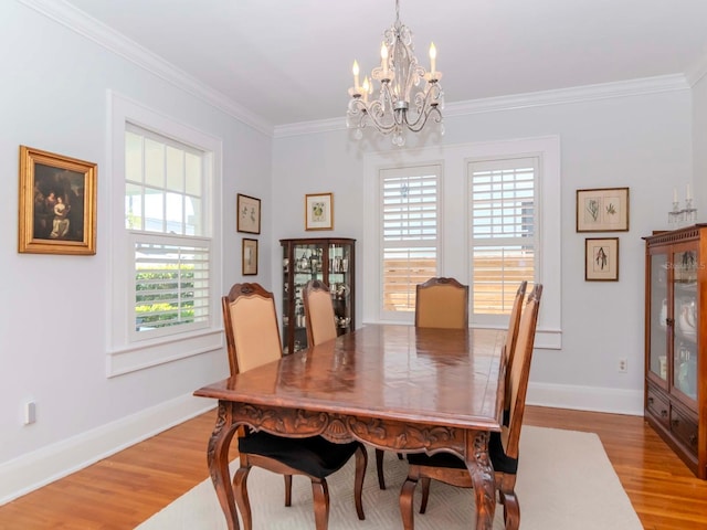 dining room featuring light wood finished floors, a chandelier, crown molding, and baseboards