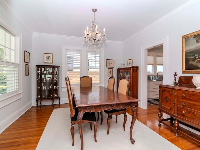 dining room with baseboards, a notable chandelier, wood finished floors, and ornamental molding