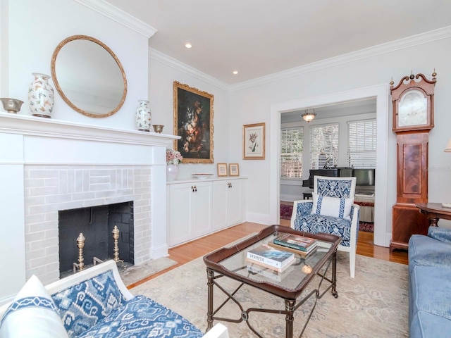 living room featuring recessed lighting, crown molding, light wood-type flooring, and a brick fireplace