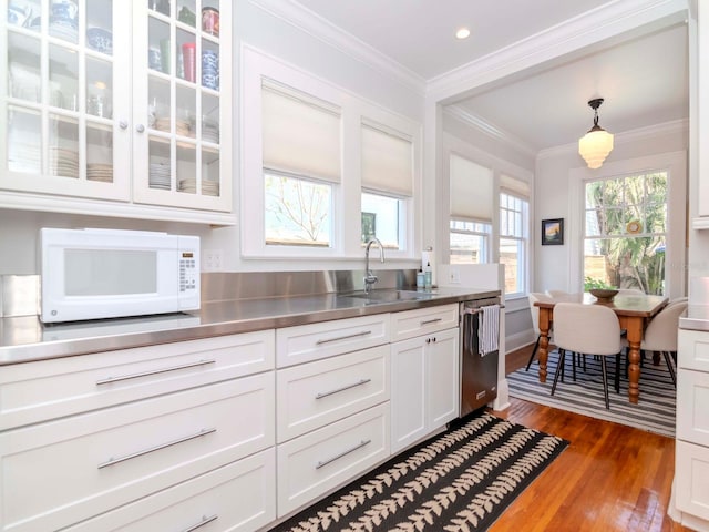 kitchen with a sink, stainless steel counters, crown molding, white microwave, and dishwasher