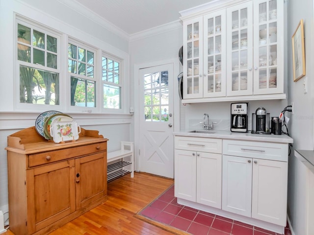 bar featuring a sink, light wood-type flooring, and ornamental molding