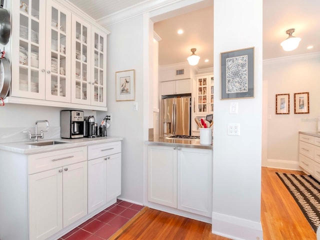 kitchen featuring visible vents, ornamental molding, a sink, stainless steel fridge, and light countertops