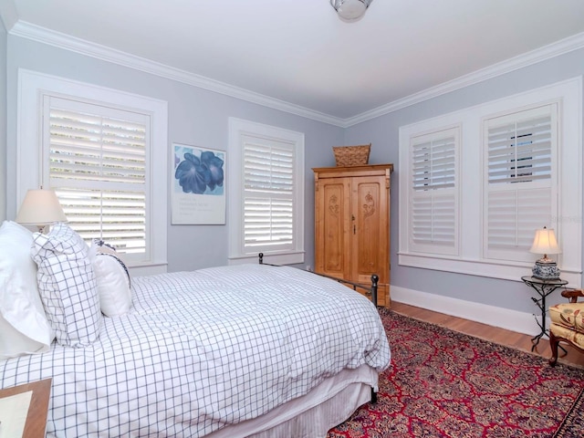 bedroom with wood finished floors, baseboards, and ornamental molding