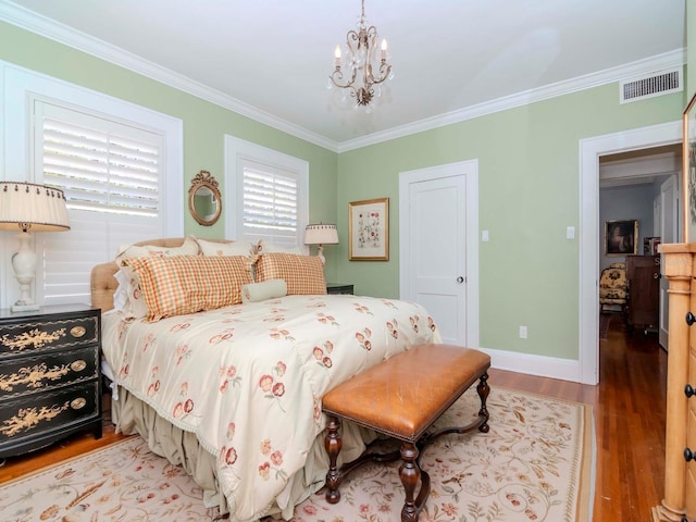 bedroom with visible vents, wood finished floors, crown molding, baseboards, and a chandelier