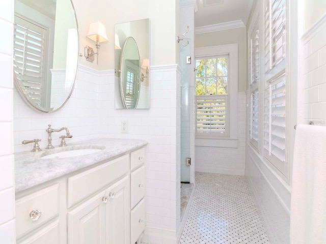 bathroom with tile patterned floors, tile walls, wainscoting, crown molding, and vanity