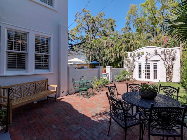 view of patio / terrace with outdoor dining space, french doors, and fence