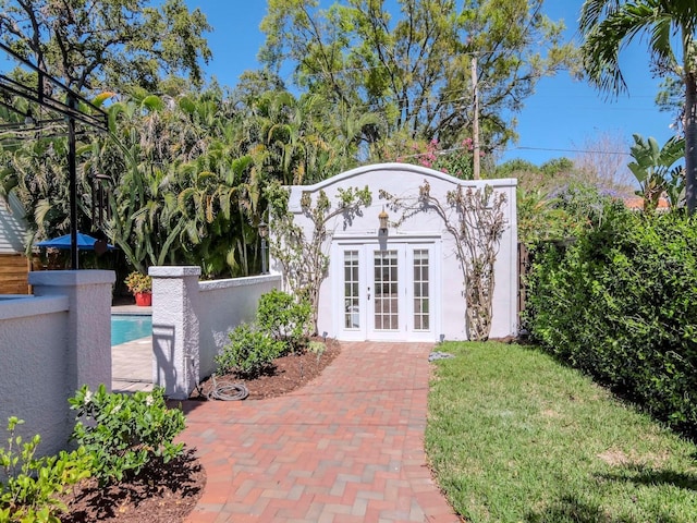 exterior space with an outbuilding, french doors, fence, and stucco siding