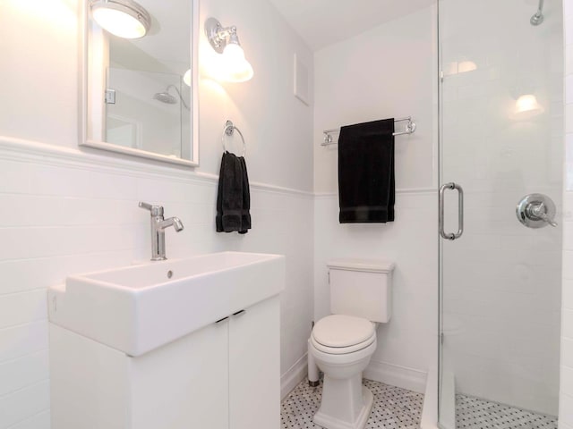 bathroom with vanity, toilet, a stall shower, and wainscoting