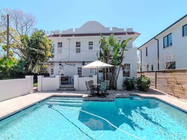 outdoor pool with outdoor dining area, a patio, and fence