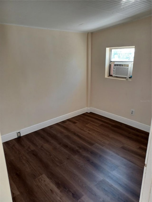 unfurnished room featuring dark wood-type flooring, cooling unit, and baseboards