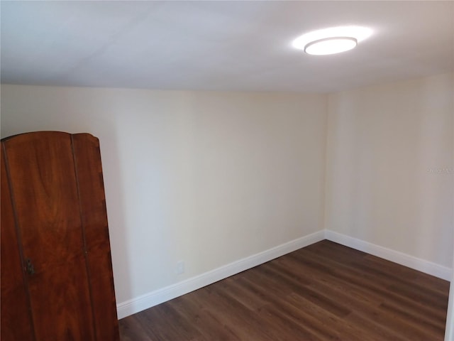 unfurnished room with dark wood-style floors and baseboards