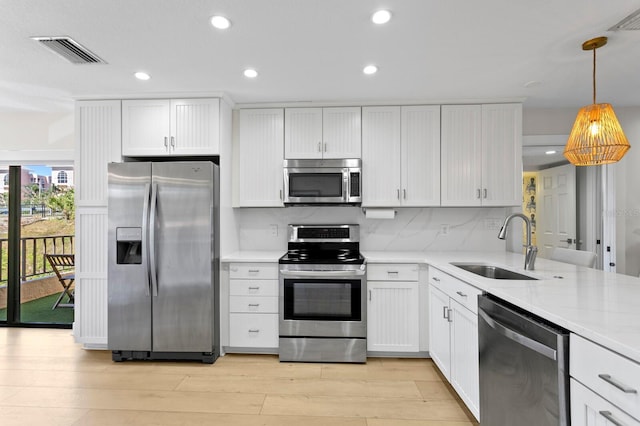 kitchen featuring light wood-style flooring, a sink, visible vents, appliances with stainless steel finishes, and backsplash