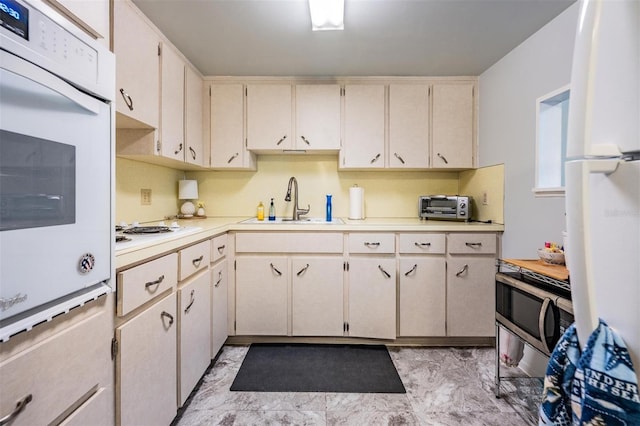 kitchen featuring a toaster, white appliances, a sink, marble finish floor, and light countertops