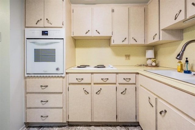 kitchen featuring white appliances, light countertops, and a sink