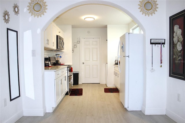 kitchen with stainless steel appliances, light wood-type flooring, white cabinets, and light countertops