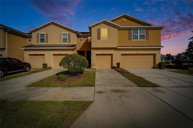 view of front of house with a garage, concrete driveway, and stucco siding