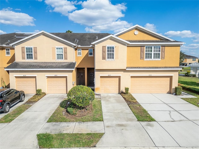 townhome / multi-family property featuring a garage, driveway, and stucco siding