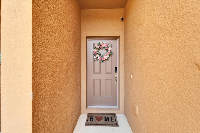 doorway to property featuring stucco siding