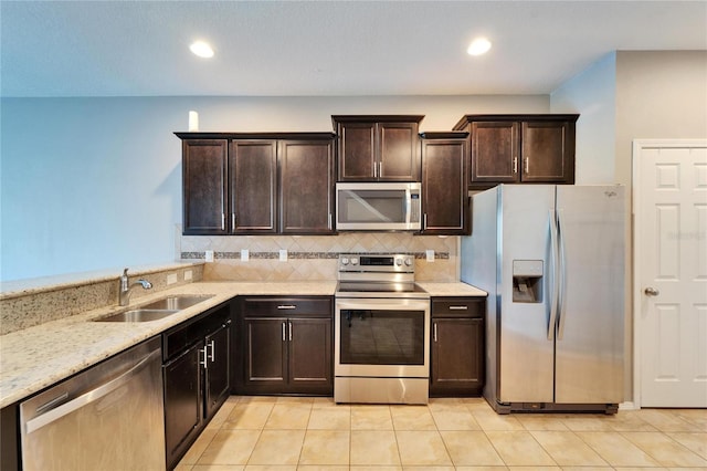 kitchen featuring appliances with stainless steel finishes, a sink, dark brown cabinetry, and tasteful backsplash