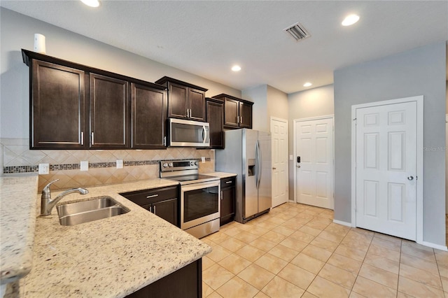 kitchen with dark brown cabinetry, a sink, visible vents, appliances with stainless steel finishes, and backsplash