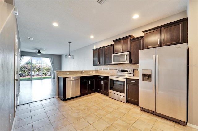 kitchen with dark brown cabinetry, appliances with stainless steel finishes, light countertops, and decorative backsplash