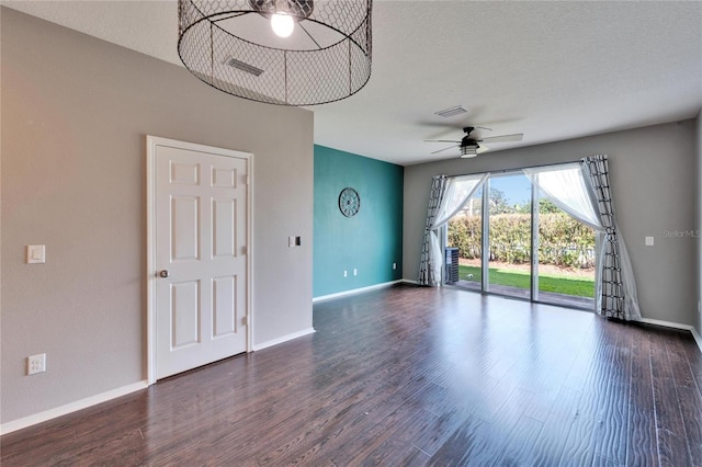 spare room with visible vents, dark wood-type flooring, a ceiling fan, a textured ceiling, and baseboards