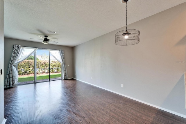 spare room with baseboards, visible vents, a ceiling fan, dark wood-type flooring, and a textured ceiling