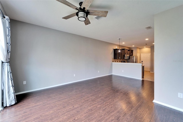 unfurnished living room featuring baseboards, visible vents, dark wood finished floors, and a ceiling fan