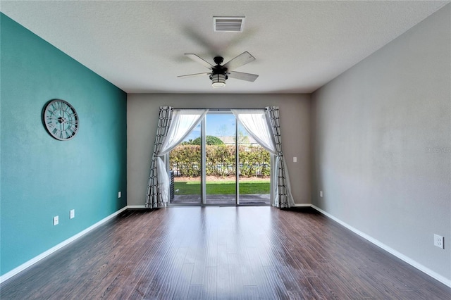 empty room with baseboards, visible vents, a ceiling fan, wood finished floors, and a textured ceiling