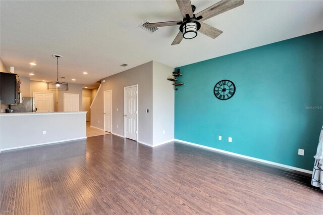 unfurnished living room featuring visible vents, baseboards, ceiling fan, and dark wood-style flooring