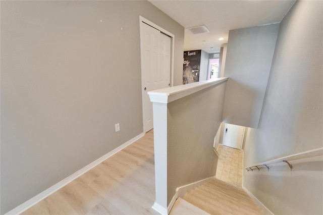 stairs with wood finished floors, visible vents, and baseboards