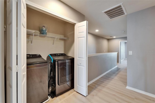 laundry room featuring washing machine and dryer, laundry area, visible vents, baseboards, and light wood-style floors