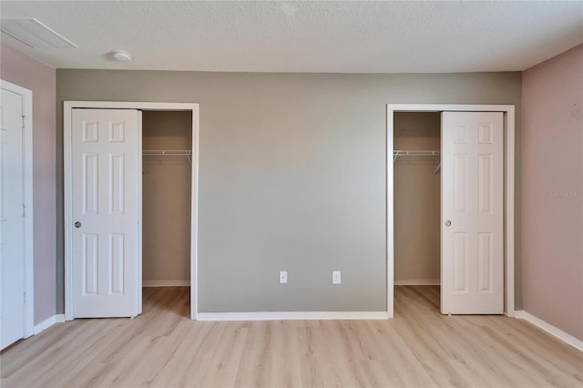 unfurnished bedroom featuring a textured ceiling, wood finished floors, visible vents, and baseboards