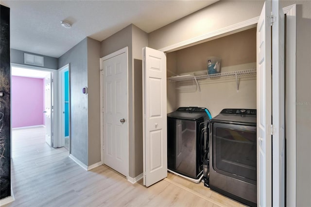 washroom featuring laundry area, visible vents, baseboards, light wood-style floors, and washing machine and clothes dryer