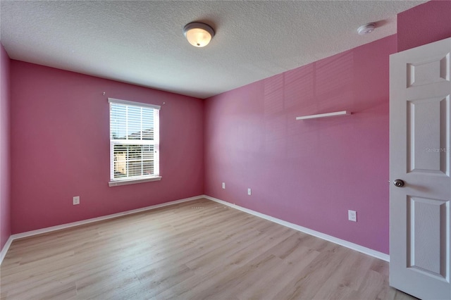 unfurnished room featuring a textured ceiling, baseboards, and light wood-style floors