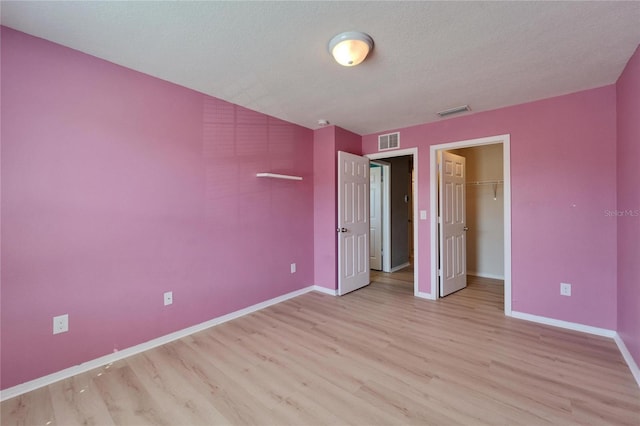 unfurnished bedroom with light wood finished floors, baseboards, visible vents, and a textured ceiling