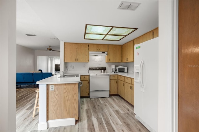 kitchen with light countertops, white appliances, a peninsula, a kitchen breakfast bar, and under cabinet range hood