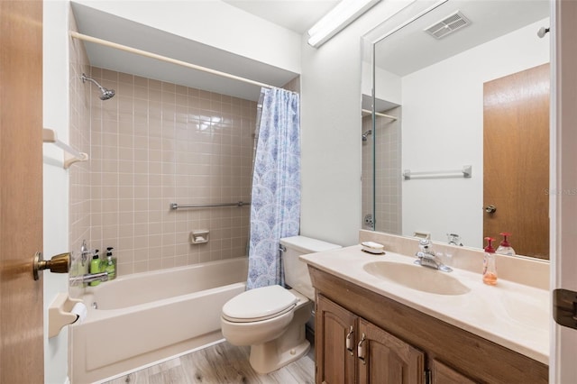 bathroom featuring visible vents, toilet, wood finished floors, shower / bathtub combination with curtain, and vanity