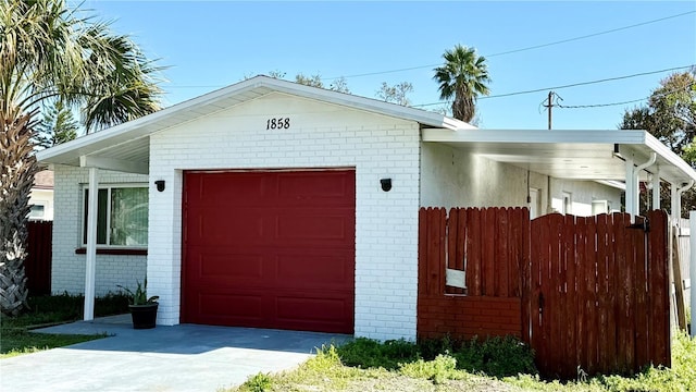 garage featuring concrete driveway and fence