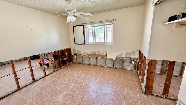 empty room featuring ceiling fan, a textured ceiling, and light tile patterned flooring